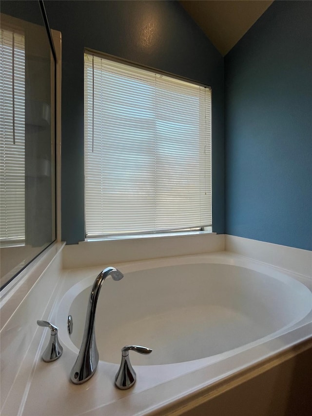 bathroom featuring lofted ceiling and a bathtub