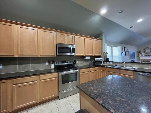 kitchen featuring light tile patterned flooring, lofted ceiling, sink, stainless steel appliances, and backsplash