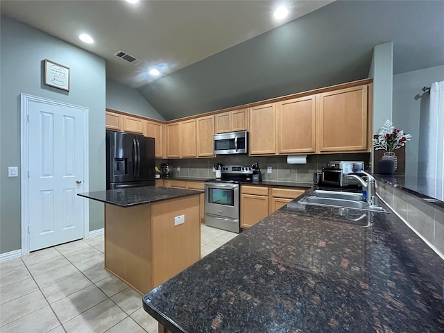 kitchen with light tile patterned flooring, appliances with stainless steel finishes, light brown cabinetry, sink, and a center island