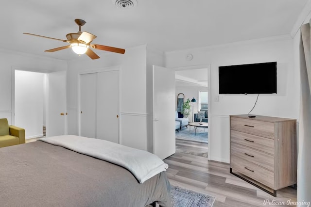 bedroom featuring a closet, ornamental molding, ceiling fan, and light hardwood / wood-style flooring