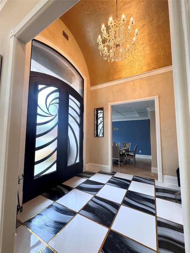 entryway featuring vaulted ceiling, ornamental molding, french doors, and a chandelier