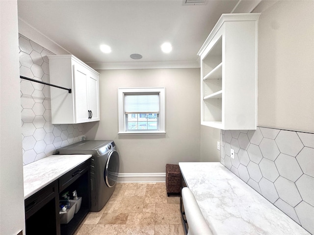 clothes washing area featuring cabinets, ornamental molding, and washer and clothes dryer