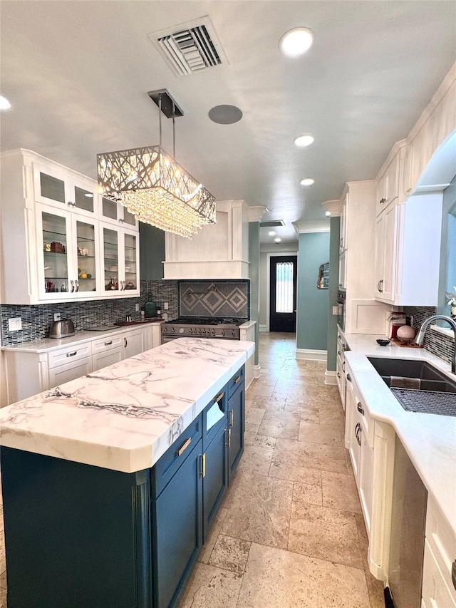 kitchen featuring blue cabinetry, sink, white cabinetry, decorative light fixtures, and a kitchen island