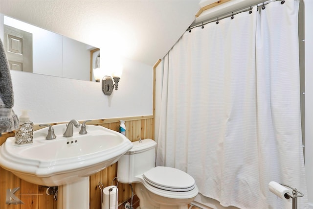 bathroom featuring a shower with shower curtain, toilet, and sink