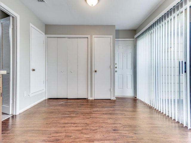 unfurnished bedroom featuring multiple closets and hardwood / wood-style flooring