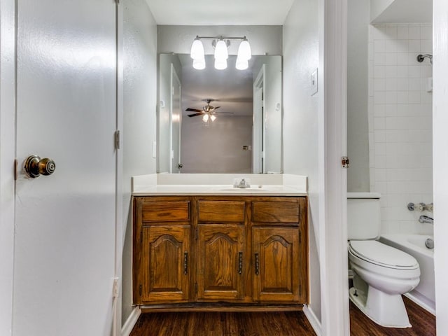 full bathroom with toilet, wood-type flooring, vanity, tiled shower / bath combo, and ceiling fan