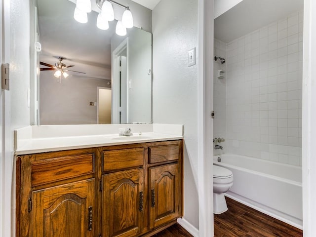 full bathroom with hardwood / wood-style flooring, ceiling fan, tiled shower / bath combo, vanity, and toilet