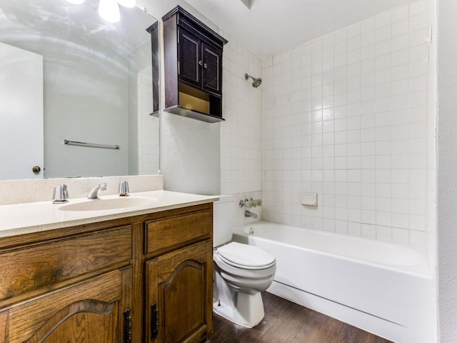 full bathroom with hardwood / wood-style flooring, vanity, tiled shower / bath combo, and toilet