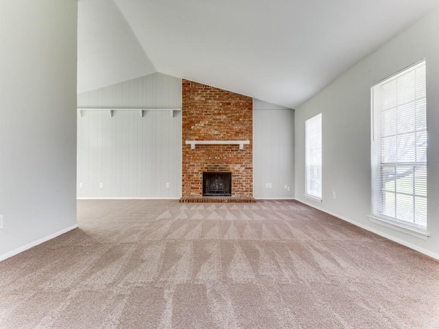 unfurnished living room with vaulted ceiling, light colored carpet, and a fireplace