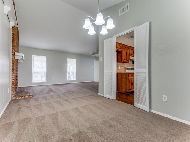 unfurnished living room with light colored carpet, a brick fireplace, and a notable chandelier