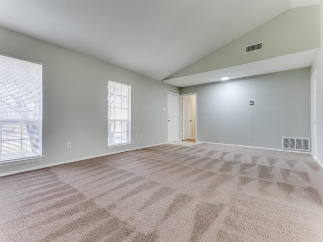 carpeted empty room with lofted ceiling and a wealth of natural light