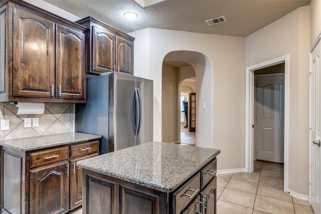 kitchen featuring dark brown cabinets, light stone countertops, and a kitchen island