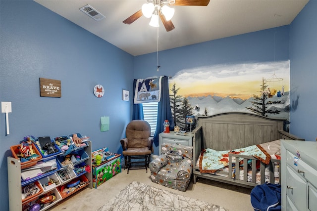 bedroom with a crib, light colored carpet, and ceiling fan