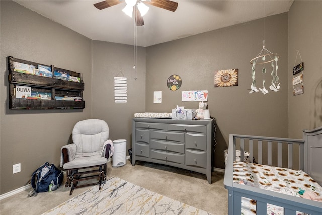 carpeted bedroom with ceiling fan and a crib