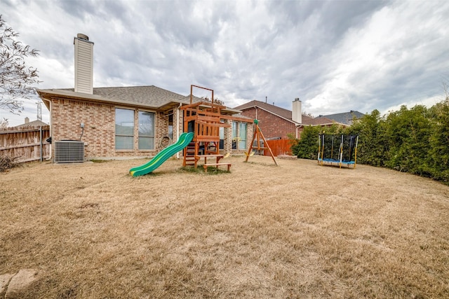 view of play area featuring central AC, a trampoline, and a lawn