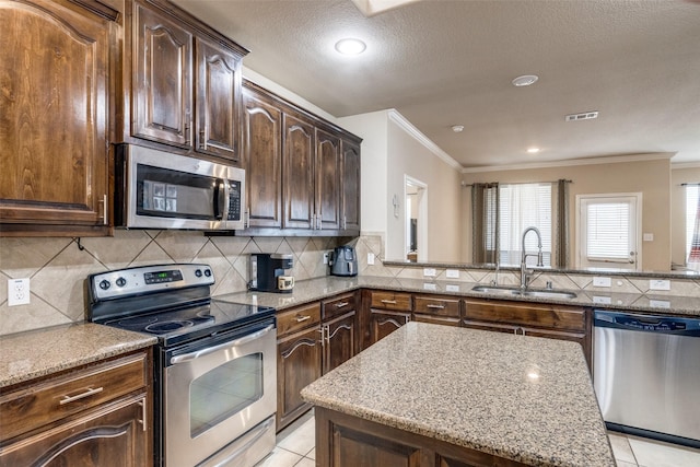 kitchen featuring appliances with stainless steel finishes, tasteful backsplash, sink, light tile patterned floors, and light stone counters