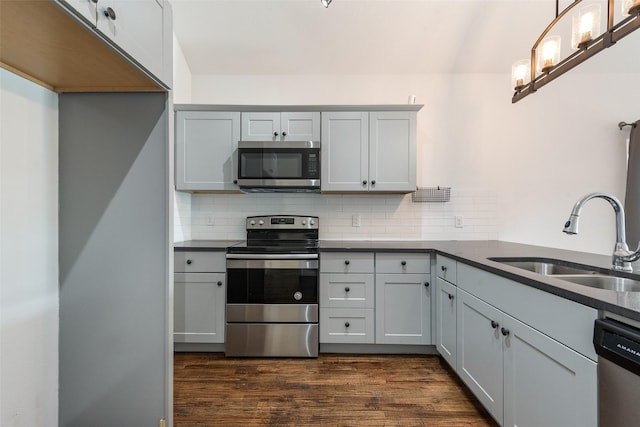 kitchen with appliances with stainless steel finishes, dark hardwood / wood-style floors, sink, and gray cabinetry