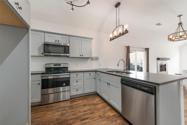 kitchen with pendant lighting, sink, kitchen peninsula, and appliances with stainless steel finishes