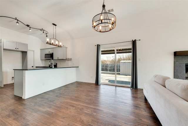 kitchen with an inviting chandelier, decorative light fixtures, dark wood-type flooring, and kitchen peninsula