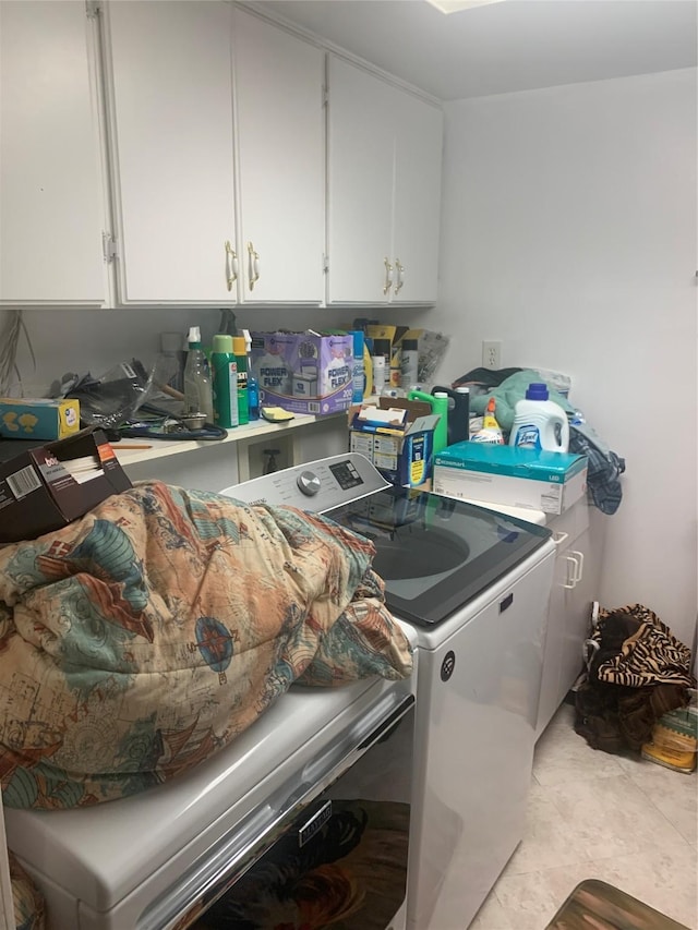 clothes washing area featuring washing machine and dryer and cabinets