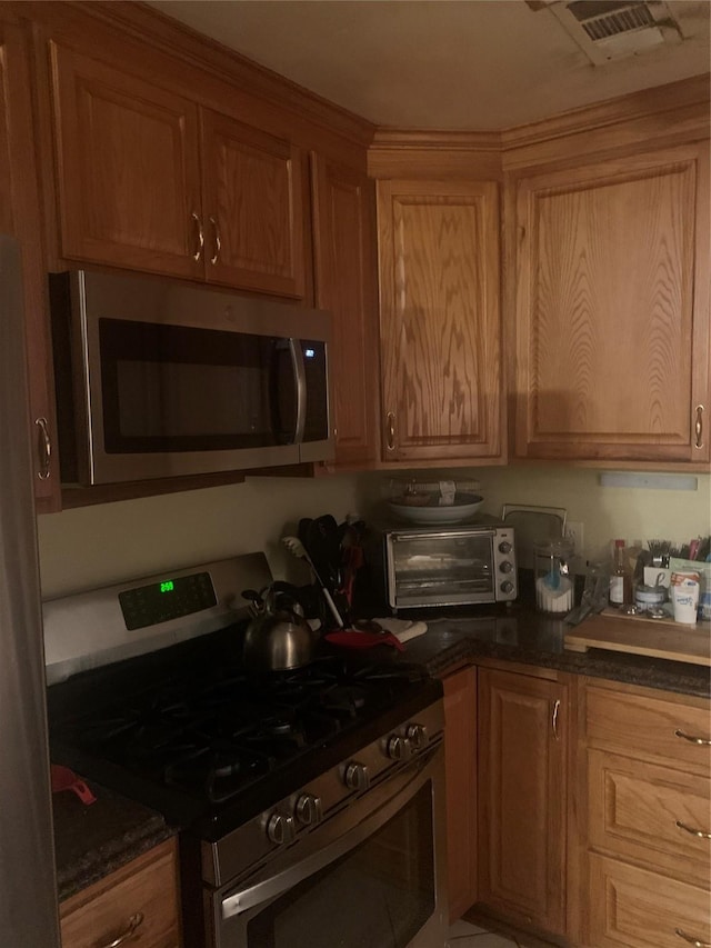 kitchen featuring appliances with stainless steel finishes and dark stone countertops