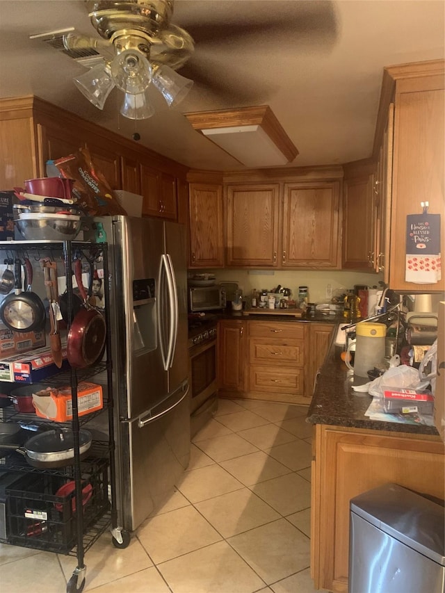 kitchen featuring ceiling fan, range, light tile patterned flooring, stainless steel fridge with ice dispenser, and dark stone counters