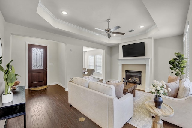 living room featuring a raised ceiling, crown molding, ceiling fan, and dark hardwood / wood-style flooring