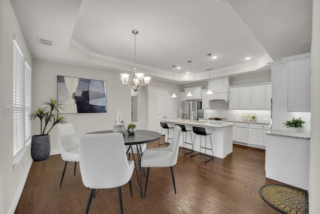 dining area with a raised ceiling, ornamental molding, and dark hardwood / wood-style flooring