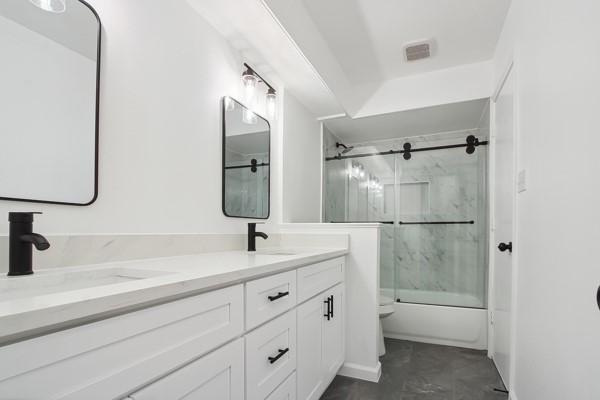 full bathroom with vanity, toilet, and combined bath / shower with glass door