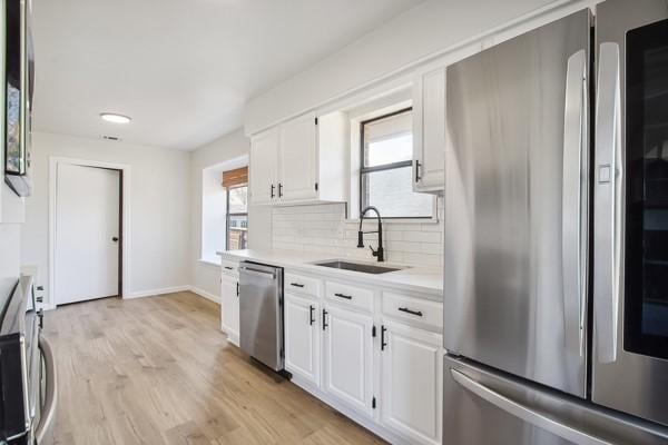 kitchen with stainless steel appliances, sink, white cabinets, and backsplash