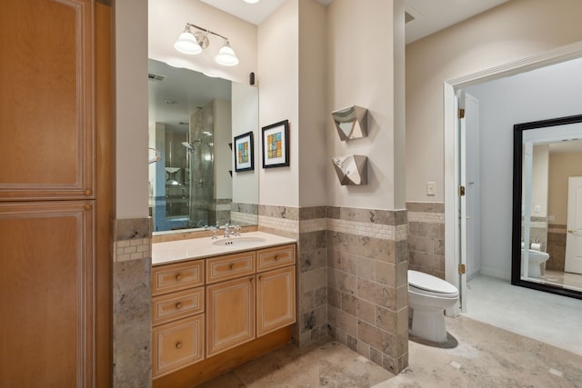 bathroom with vanity, toilet, a shower with shower door, and tile walls