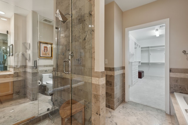 bathroom with toilet, shower with separate bathtub, and tile walls