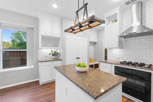 kitchen featuring a kitchen island, decorative light fixtures, white cabinetry, oven, and wall chimney exhaust hood