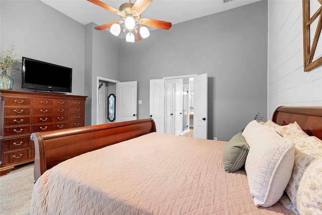 bedroom featuring a high ceiling, light carpet, and ceiling fan