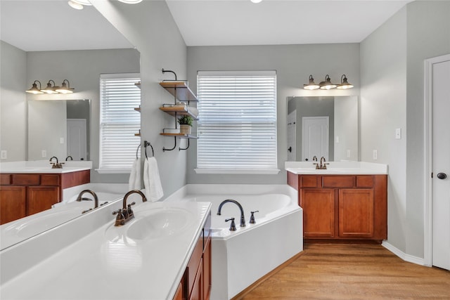 bathroom with wood-type flooring, a bath, and vanity