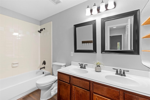 full bathroom with tiled shower / bath, vanity, and toilet