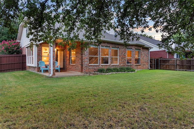 back house at dusk with a yard and a patio