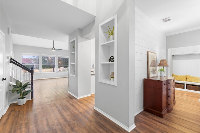 hallway with ornamental molding, dark wood-type flooring, and built in features