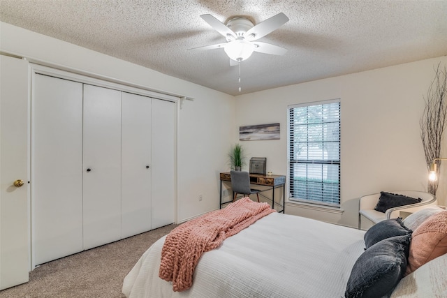 bedroom with ceiling fan, light colored carpet, a closet, and a textured ceiling