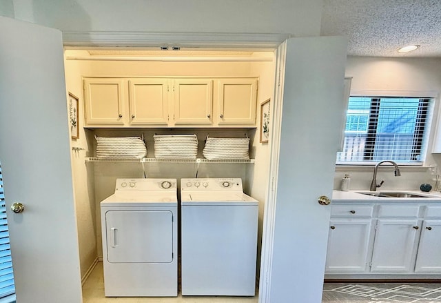 laundry area featuring cabinets, sink, washing machine and dryer, and a textured ceiling