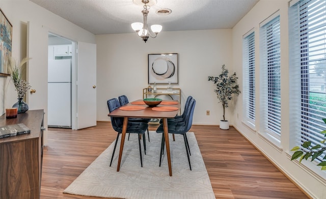 dining room featuring a notable chandelier, a textured ceiling, and light hardwood / wood-style flooring