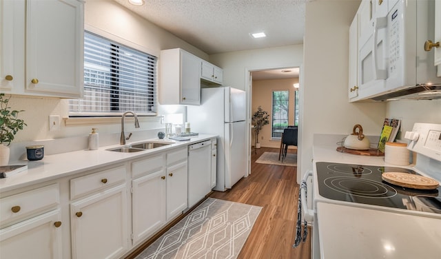 kitchen with sink, white cabinets, white appliances, light hardwood / wood-style floors, and a textured ceiling