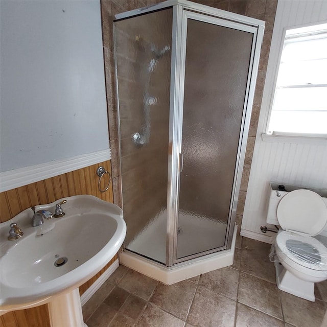 bathroom featuring wood walls, sink, an enclosed shower, and toilet