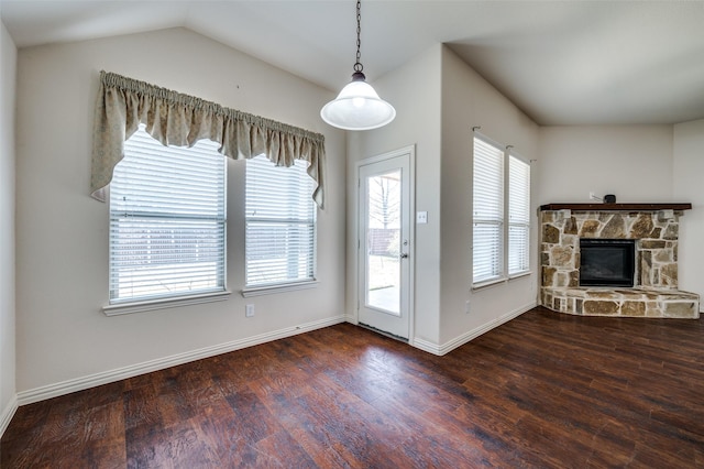 unfurnished living room with a stone fireplace, lofted ceiling, baseboards, and wood finished floors