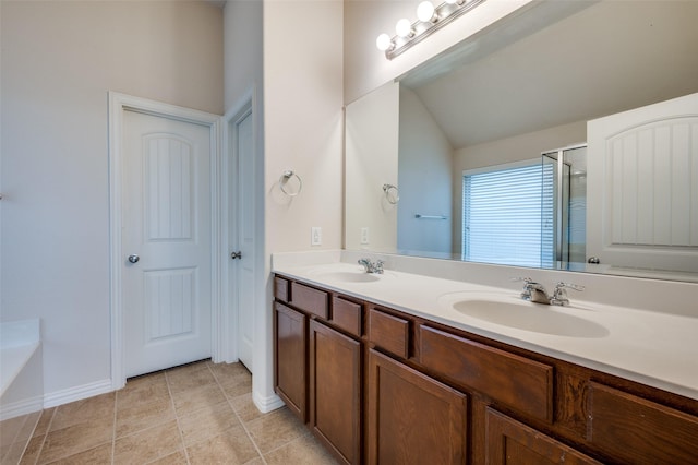 full bath featuring a sink, a stall shower, double vanity, and tile patterned flooring