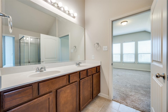 bathroom featuring lofted ceiling, double vanity, a stall shower, a sink, and tile patterned flooring