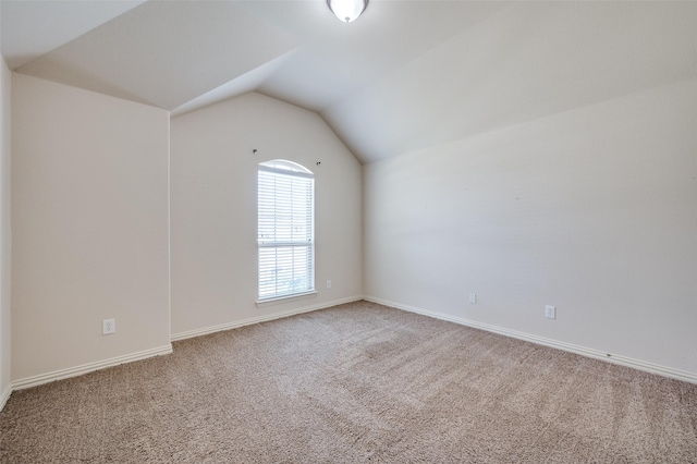 carpeted spare room with lofted ceiling and baseboards