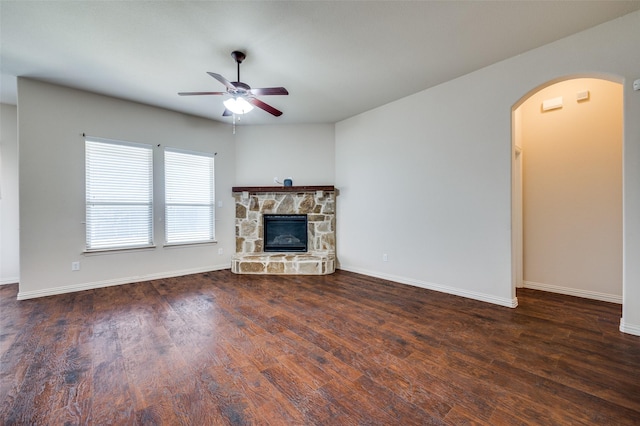 unfurnished living room with baseboards, wood finished floors, arched walkways, and ceiling fan