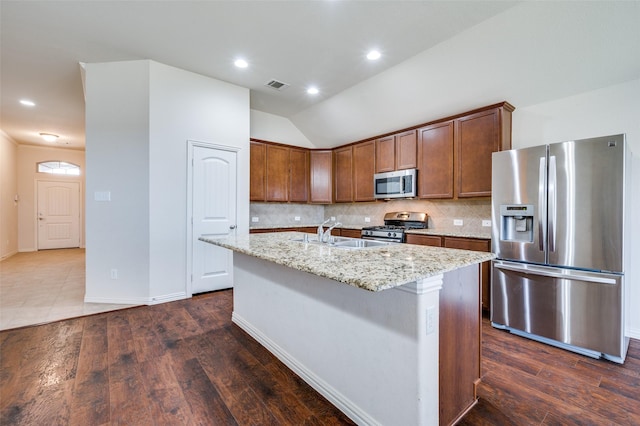 kitchen with dark wood-style floors, light stone countertops, visible vents, stainless steel appliances, and tasteful backsplash