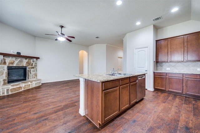 kitchen with visible vents, a sink, dark wood-type flooring, arched walkways, and stainless steel dishwasher